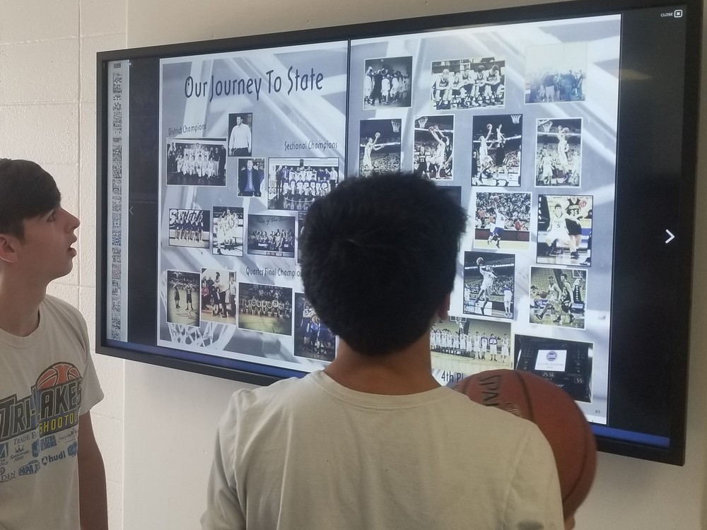 Two students viewing a yearbook from 2014 on the new Touch Wall 